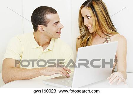 Close-up of a young couple looking at each other in front of a laptop View Large Photo Image Stock Image - Close-up of a young couple looking at each other in front of a laptop. Fotosearch