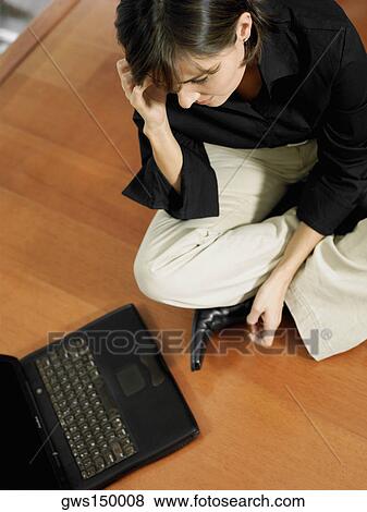 Stock Photo - High angle view of a businesswoman talking on a mobile phone and sitting in front of a laptop. Fotosearch