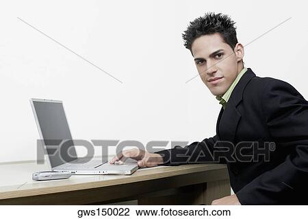 Stock Image - Portrait of a businessman sitting in front of a laptop. Fotosearch
