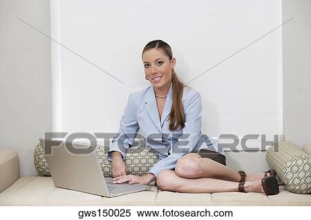 Portrait of a businesswoman sitting on a couch and using a laptop View Large Photo Image Stock Photography - Portrait of a businesswoman sitting on a couch and using a laptop. Fotosearch