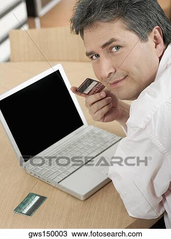 Stock Image - Portrait of a mature man holding a credit card. Fotosearch