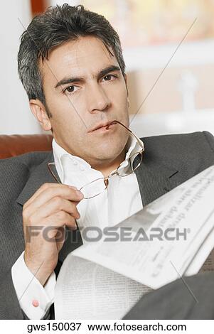 Stock Photo - Portrait of a mature man holding a newspaper and a pair of eyeglasses. Fotosearch