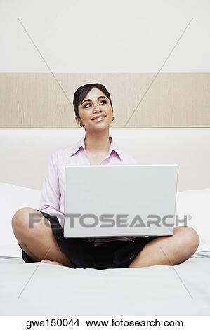 Teenage girl sitting on the bed with a laptop View Large Photo Image Picture - Teenage girl sitting on the bed with a laptop. Fotosearch