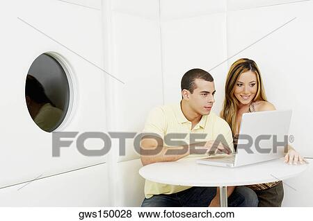 Young couple using a laptop View Large Photo Image Stock Photo - Young couple using a laptop. Fotosearch