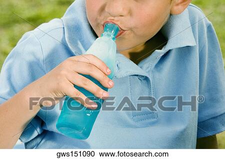 Stock Image - Close-up of a boy drinking water from a bottle. Fotosearch