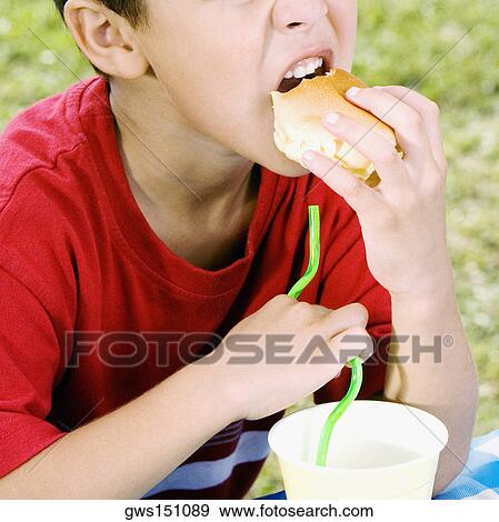 Close-up of a boy eating a burger View Large Photo Image Stock Photo - Close-up of a boy eating a burger. Fotosearch
