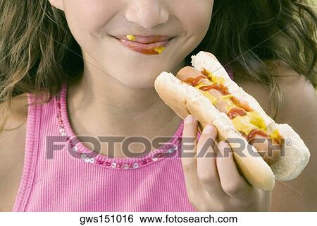 Close-up of a girl eating a hot dog View Large Photo Image Stock Photograph - Close-up of a girl eating a hot dog. Fotosearch