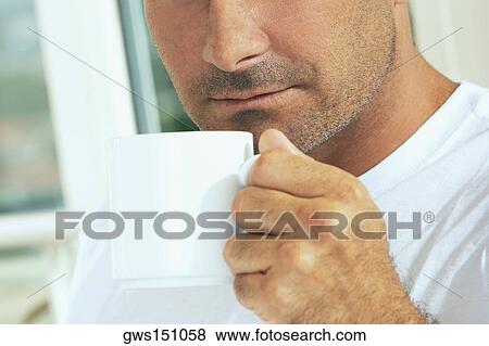 Close-up of a mid adult man holding a cup of coffee View Large Photo Image Stock Photo - Close-up of a mid adult man holding a cup of coffee. Fotosearch