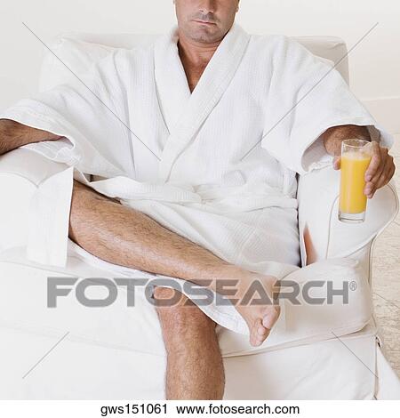 Close-up of a mid adult man sitting in an armchair and holding a glass of orange juice View Large Photo Image Stock Image - Close-up of a mid adult man sitting in an armchair and holding a glass of orange juice. Fotosearch