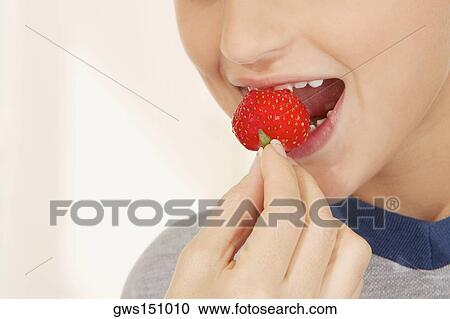 Stock Image - Close-up of a teenage girl eating a strawberry. Fotosearch