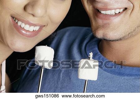 Close-up of a young couple with two marshmallows on skewers View Large Photo Image Stock Photograph - Close-up of a young couple with two marshmallows on skewers. Fotosearch