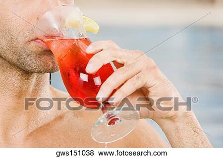Close-up of a young man drinking a glass of cocktail View Large Photo Image Stock Photo - Close-up of a young man drinking a glass of cocktail. Fotosearch
