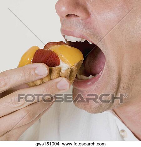 Close-up of a young man eating a fruit tart View Large Photo Image Picture - Close-up of a young man eating a fruit tart. Fotosearch