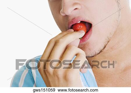 Close-up of a young man eating a strawberry View Large Photo Image Stock Photo - Close-up of a young man eating a strawberry. Fotosearch