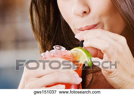 Close-up of a young woman drinking a glass of cocktail View Large Photo Image Stock Photo - Close-up of a young woman drinking a glass of cocktail. Fotosearch