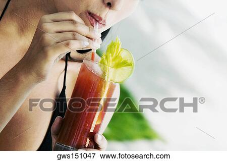 Close-up of a young woman drinking a bloody mary View Large Photo Image Stock Photo - Close-up of a young woman drinking a bloody mary. Fotosearch