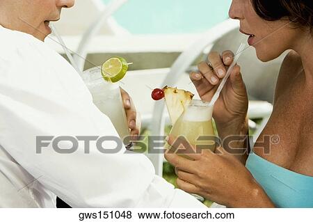 Close-up of a young woman drinking a glass of pineapple juice with a young man drinking a glass of cocktail View Large Photo Image Stock Photo - Close-up of a young woman drinking a glass of pineapple juice with a young man drinking a glass of cocktail. Fotosearch