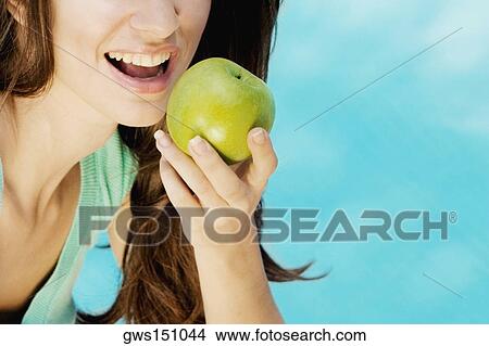 Close-up of a young woman eating a green apple View Large Photo Image Picture - Close-up of a young woman eating a green apple. Fotosearch
