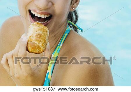 Stock Photo - Close-up of a young woman eating a puff pastry. Fotosearch