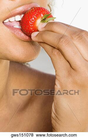 Stock Photo - Close-up of a young woman eating a strawberry. Fotosearch