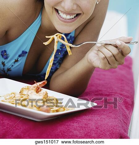 Stock Photo - Close-up of a young woman eating pasta with a fork. Fotosearch