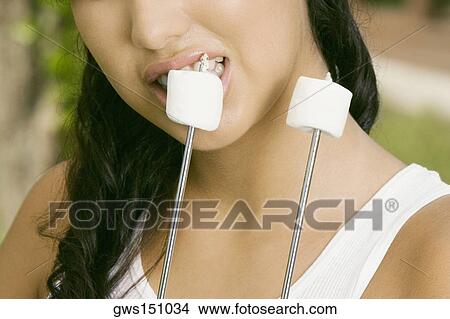 Close-up of a young woman eating marshmallows View Large Photo Image Picture - Close-up of a young woman eating marshmallows. Fotosearch