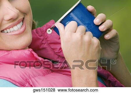 Close-up of a young woman holding a cup and smiling View Large Photo Image Stock Photo - Close-up of a young woman holding a cup and smiling. Fotosearch