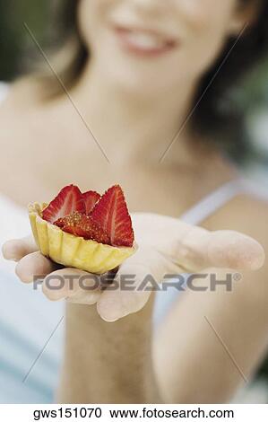 Close-up of a young woman holding a strawberry tart and smiling View Large Photo Image Stock Image - Close-up of a young woman holding a strawberry tart and smiling. Fotosearch
