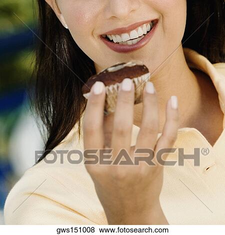 Close-up of a young woman holding a cupcake and smiling View Large Photo Image Stock Photo - Close-up of a young woman holding a cupcake and smiling. Fotosearch