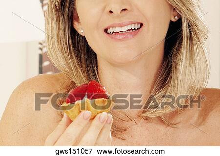 Close-up of a young woman holding a strawberry tart View Large Photo Image Stock Photo - Close-up of a young woman holding a strawberry tart. Fotosearch