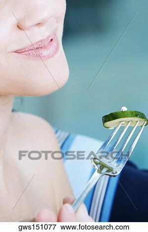 Close-up of a young woman holding a slice of cucumber with a fork View Large Photo Image Stock Photo - Close-up of a young woman holding a slice of cucumber with a fork. Fotosearch
