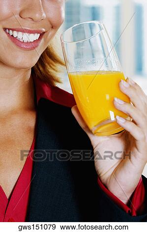 Close-up of a young woman holding a glass of orange juice and smiling View Large Photo Image Stock Photo - Close-up of a young woman holding a glass of orange juice and smiling. Fotosearch