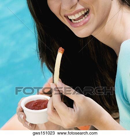 Close-up of a young woman holding French fries with dip and smiling View Large Photo Image Stock Image - Close-up of a young woman holding French fries with dip and smiling. Fotosearch