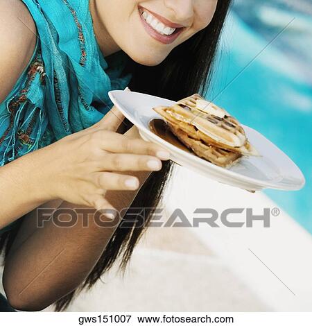 Stock Photo - Close-up of a young woman holding waffles in a plate. Fotosearch