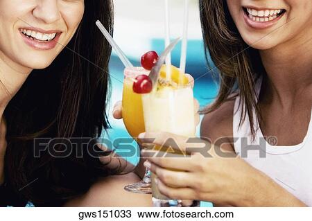 Close-up of two young women toasting two glasses of juice and smiling View Large Photo Image Stock Image - Close-up of two young women toasting two glasses of juice and smiling. Fotosearch