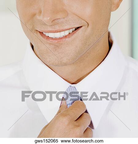Close-up of a businessman adjusting his tie and smiling View Large Photo Image Stock Photography - Close-up of a businessman adjusting his tie and smiling. Fotosearch