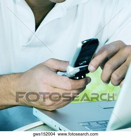 Close-up of a businessman holding a mobile phone View Large Photo Image Picture - Close-up of a businessman holding a mobile phone. Fotosearch