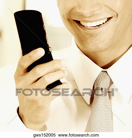 Close-up of a businessman holding a mobile phone and smiling View Large Photo Image Stock Photography - Close-up of a businessman holding a mobile phone and smiling. Fotosearch