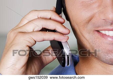 Stock Photo - Close-up of a businessman talking on a mobile phone and smiling. Fotosearch