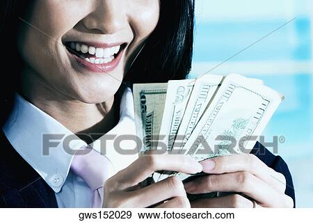 Close-up of a businesswoman counting dollar bills and smiling View Large Photo Image Stock Photo - Close-up of a businesswoman counting dollar bills and smiling. Fotosearch