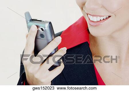 Stock Image - Close-up of a businesswoman holding a mobile phone and smiling. Fotosearch