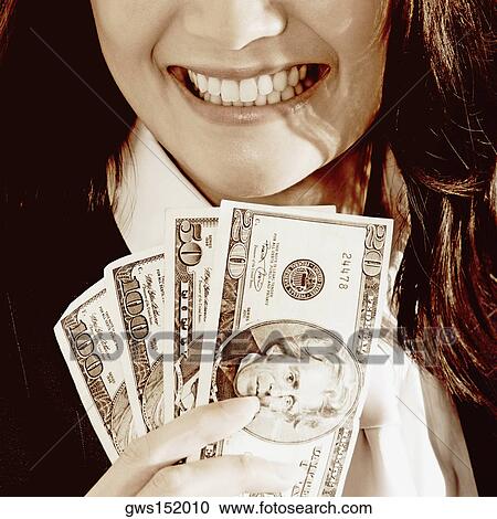 Close-up of a businesswoman holding dollar bills and smiling View Large Photo Image Stock Image - Close-up of a businesswoman holding dollar bills and smiling. Fotosearch
