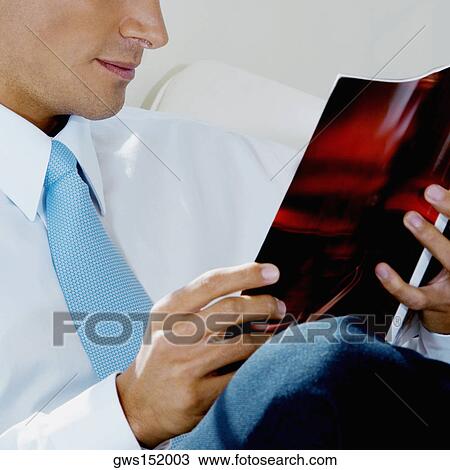 Mid section view of a businessman reading a magazine View Large Photo Image Stock Image - Mid section view of a businessman reading a magazine. Fotosearch