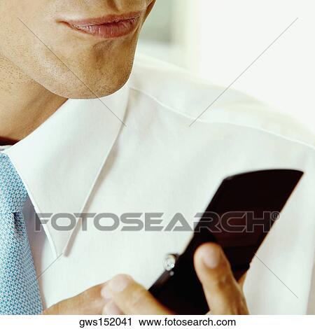 Mid section view of a businessman holding a mobile phone View Large Photo Image Stock Image - Mid section view of a businessman holding a mobile phone. Fotosearch