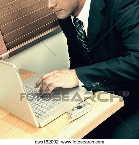 Stock Image - Mid section view of a businessman using a laptop. Fotosearch