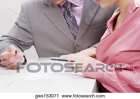 Close-up of a businesswoman holding a credit card with a businessman beside her View Large Photo Image Stock Image - Close-up of a businesswoman holding a credit card with a businessman beside her. Fotosearch