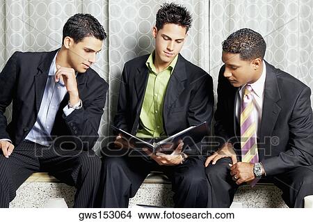 Close-up of three businessmen reading a file View Large Photo Image Picture - Close-up of three businessmen reading a file. Fotosearch