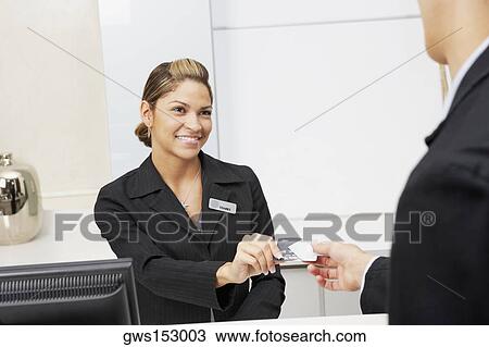 Stock Image - Customer giving a credit card to a female receptionist. Fotosearch