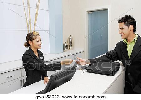 Customer giving a credit card to a female receptionist View Large Photo Image Stock Image - Customer giving a credit card to a female receptionist. Fotosearch