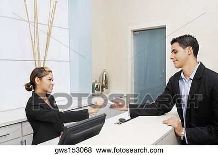 Stock Photo - Customer giving a credit card to a female receptionist. Fotosearch